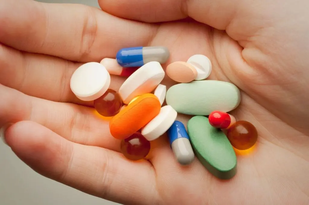 Hand holding various pills, illustrating the effects of fentanyl addiction and its dangers.