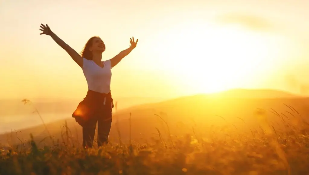 Person embracing the sunrise, symbolizing forgiving after addiction and the journey of recovery.