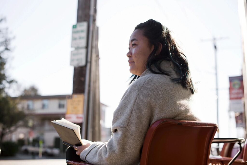 Person reading a book outdoors, reflecting on what it means to be sober and embracing sobriety.