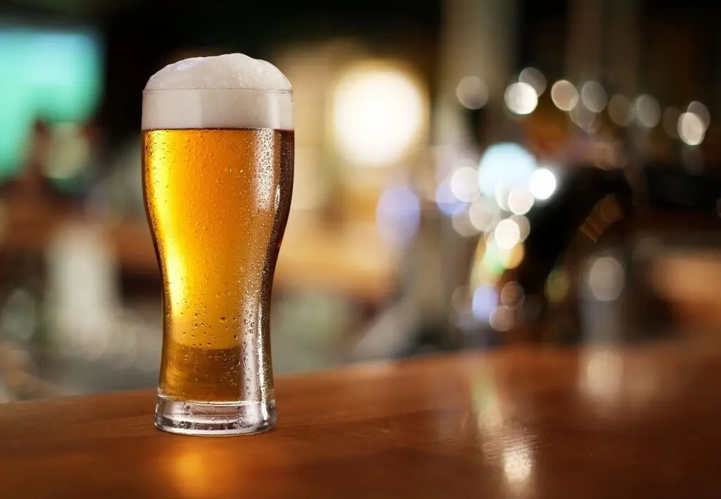 Glass of beer on a bar counter, highlighting alcohol addiction warning signs and the dangers of alcoholism.